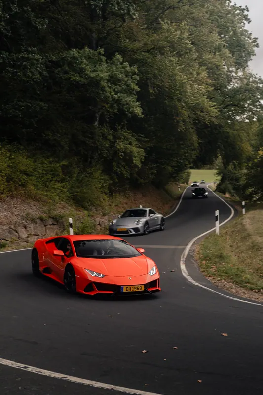 An orange Lamborghini followed by other cars