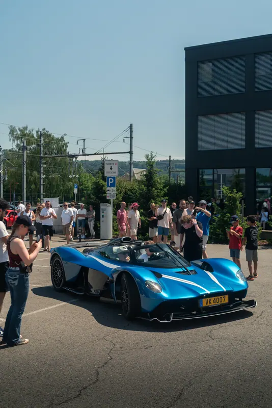 Visitors alongside a blue supercar